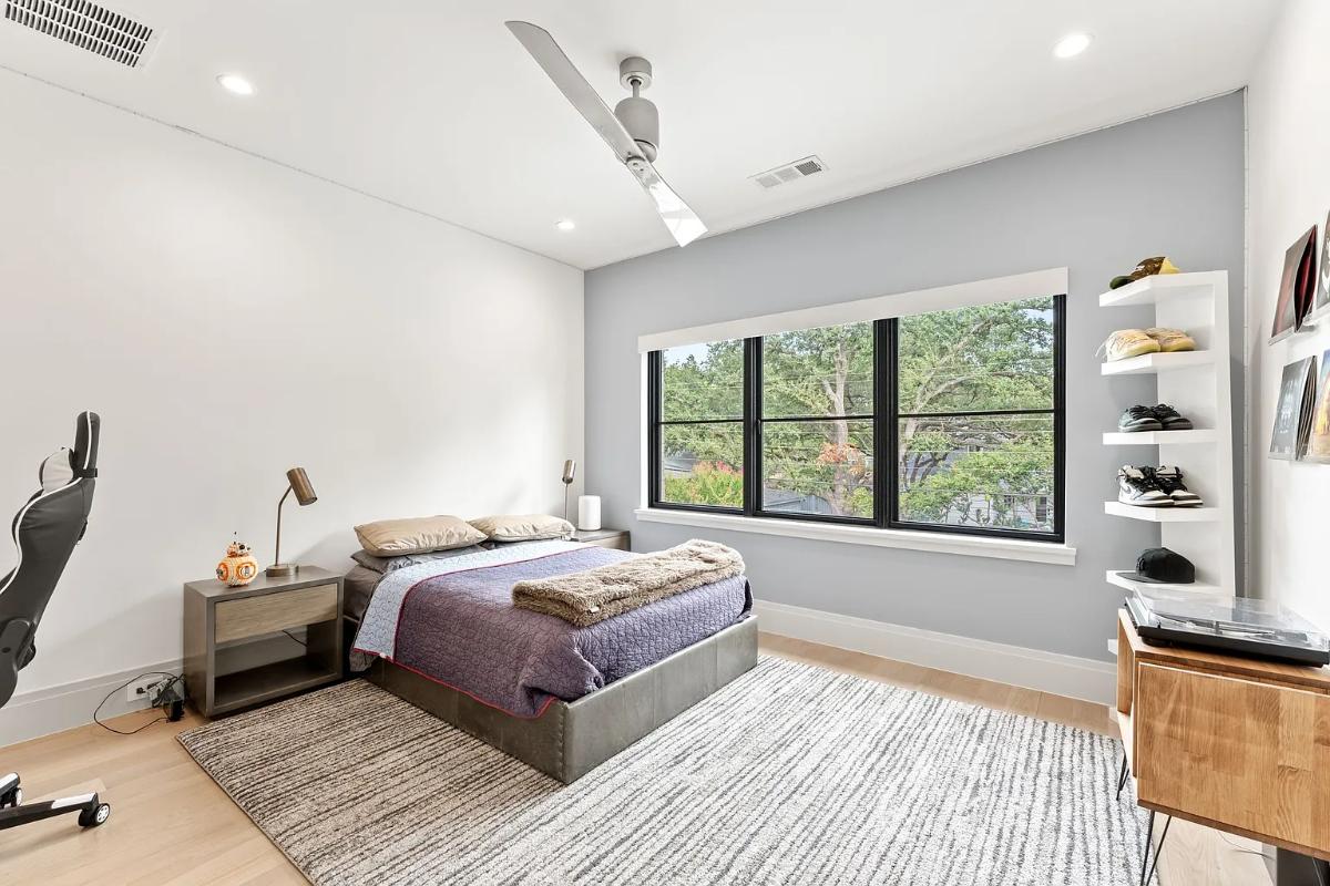 Bedroom with a large bed, glass windows and hardwood floors.