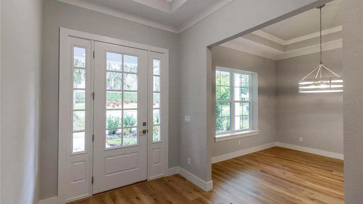 A foyer with windows and a wooden floor.