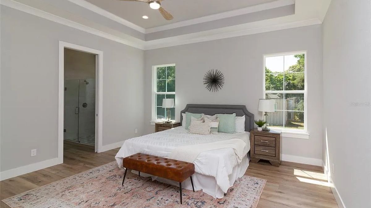 A bedroom with a bed, nightstand, and windows.