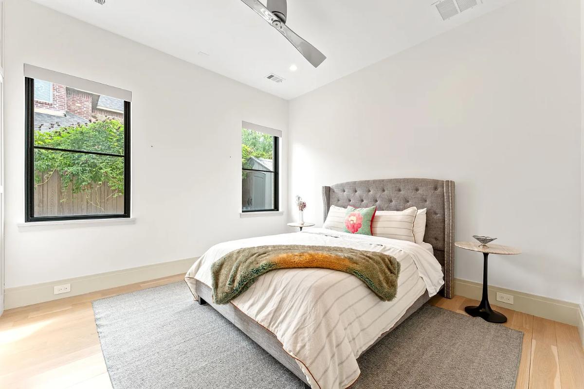 Bedroom with a large bed, glass windows and hardwood floors.