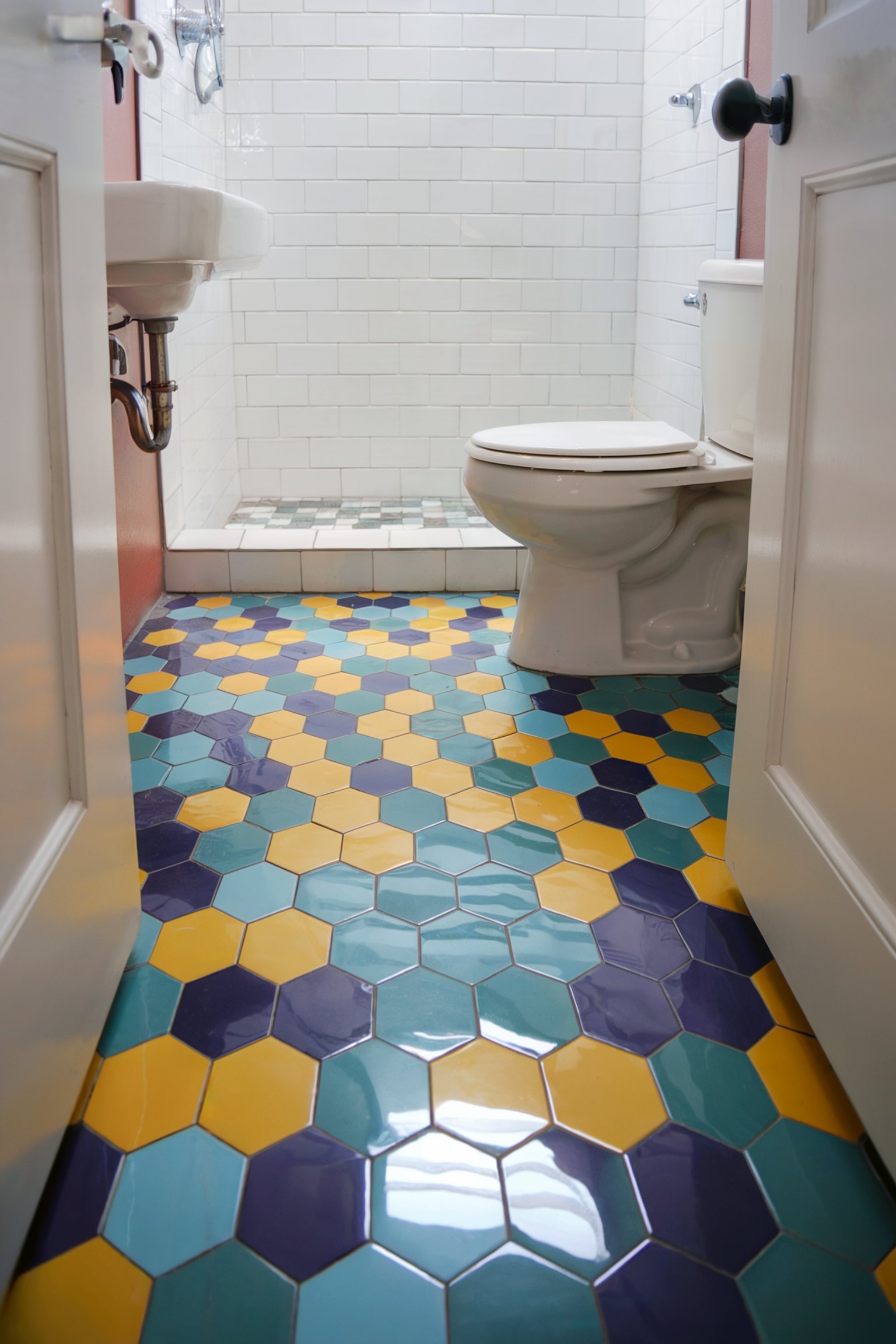 A compact bathroom featuring vibrant, hexagonal floor tiles in shades of teal, yellow, and deep blue