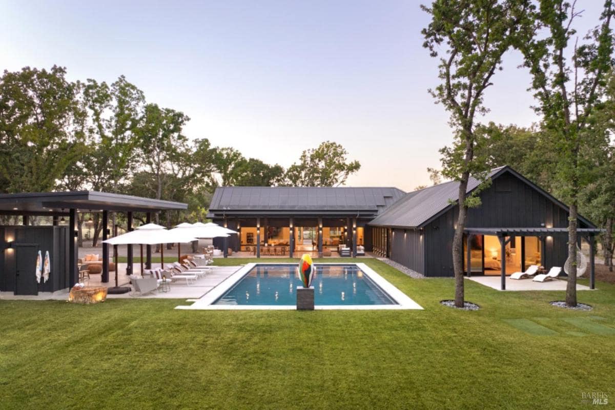 A modern house with dark exteriors, large windows, a central pool, and surrounding patios.