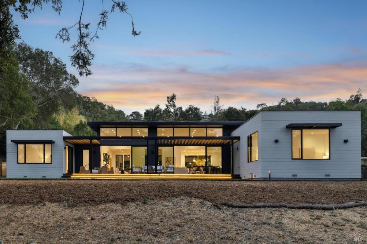 A modern home with large windows and open design at sunset.