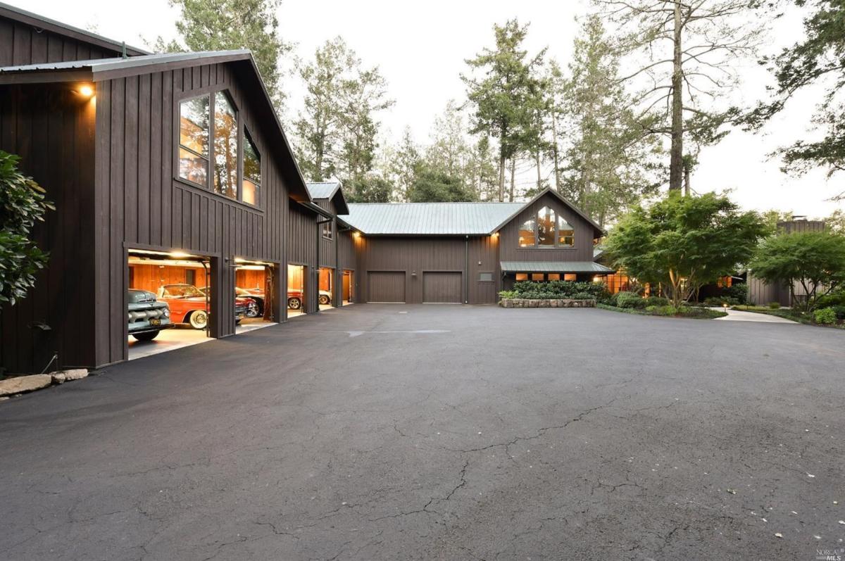 A driveway leading to a house with multiple garage doors and a landscaped front.