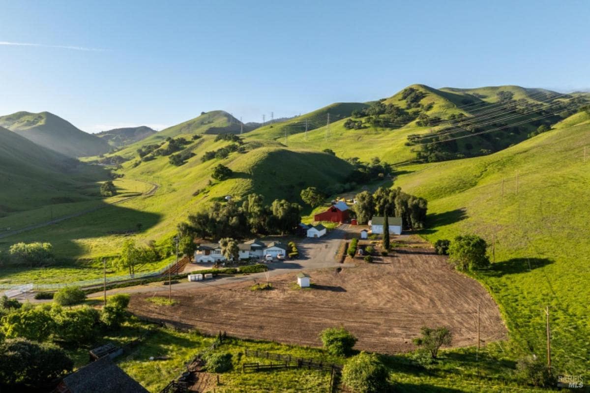 Aerial view of a property with hills and a barn.