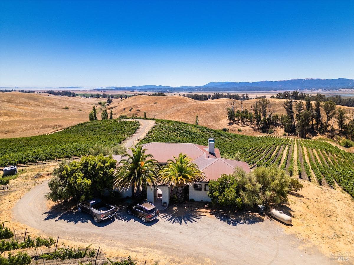 Aerial view of a vineyard estate with a circular driveway and surrounding rolling hills.