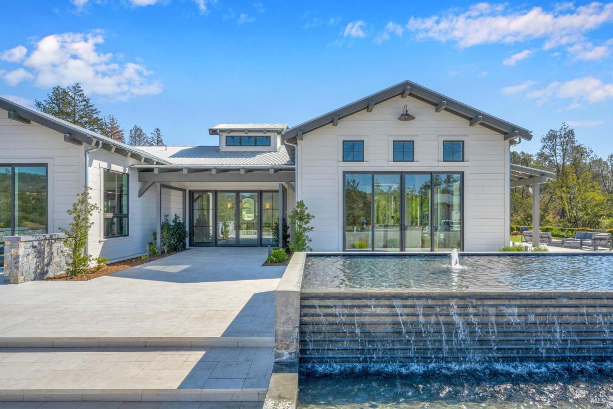 Modern white home exterior with a cascading water feature and large glass doors.