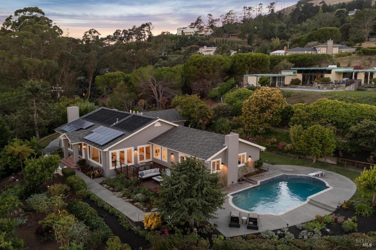 An aerial view of a single-story house with a pool and landscaped garden.