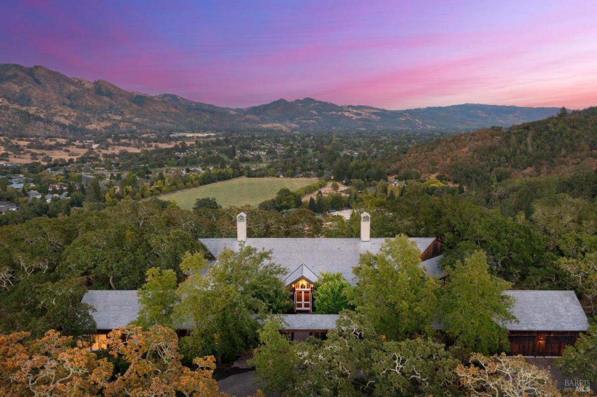 Aerial view of a large estate surrounded by trees and hills, overlooking a valley.