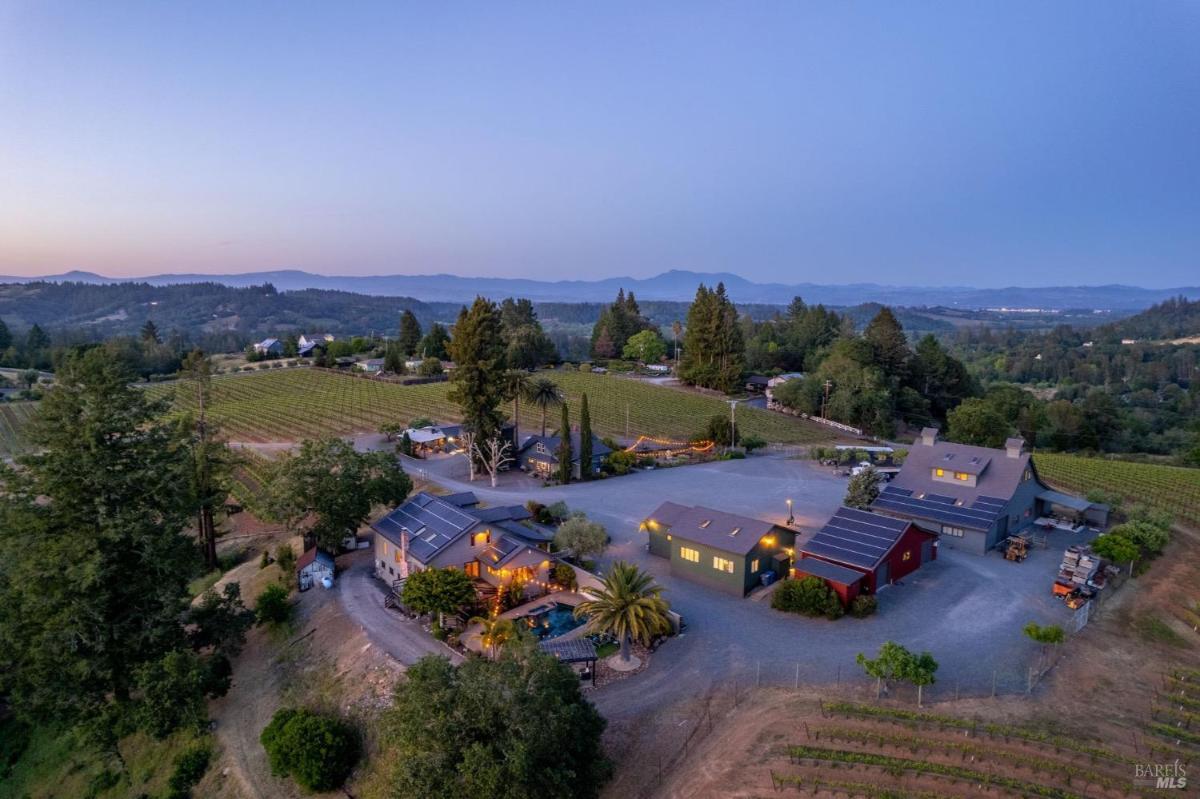 Aerial view of a vineyard property with multiple buildings and surrounding hills.