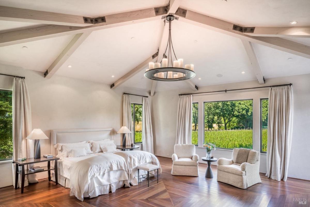 Bedroom with a large bed, two comfortable chairs, and stylish lighting. 