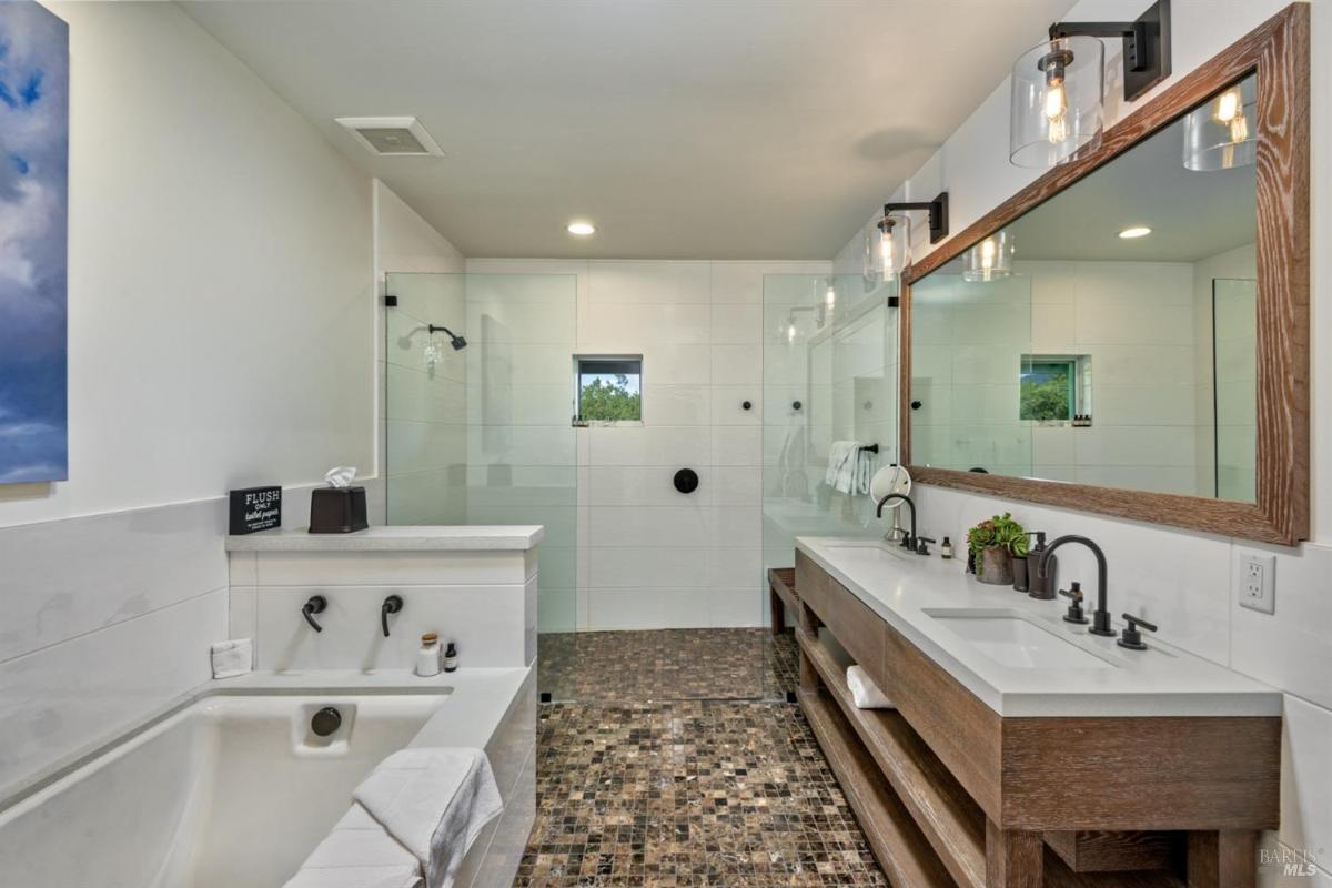 Bathroom with a tub, walk-in shower, double vanity, and large mirror.