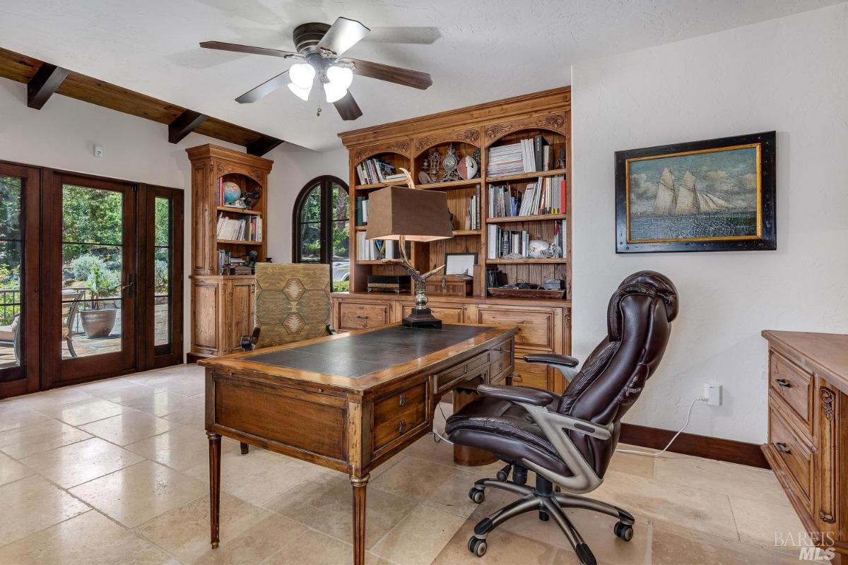 A study with wooden shelves, a desk, and French doors leading outside.