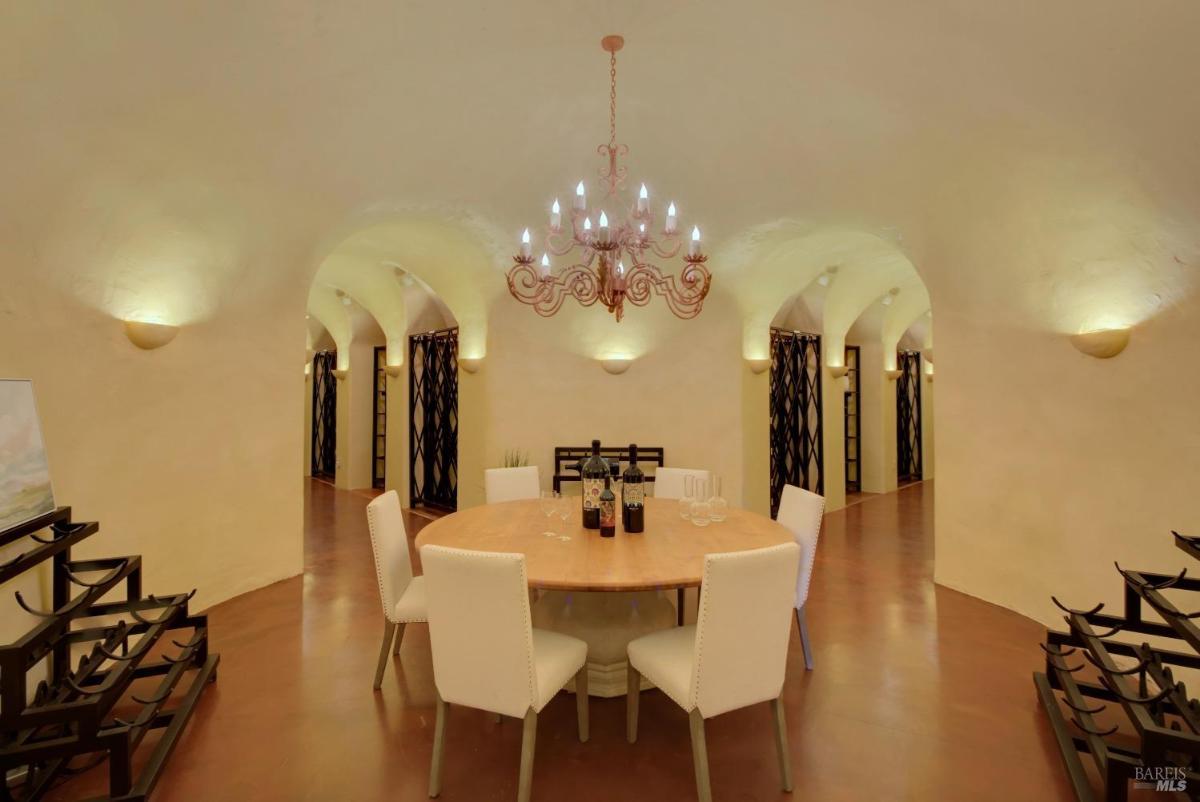 A wine cellar dining area with a round table, chairs, and arched walls.