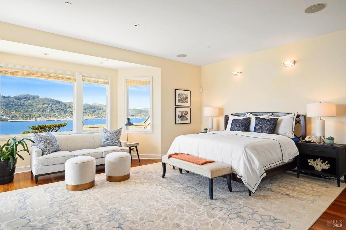 Bedroom with a large bed, sitting area, and wide windows showing ocean views.