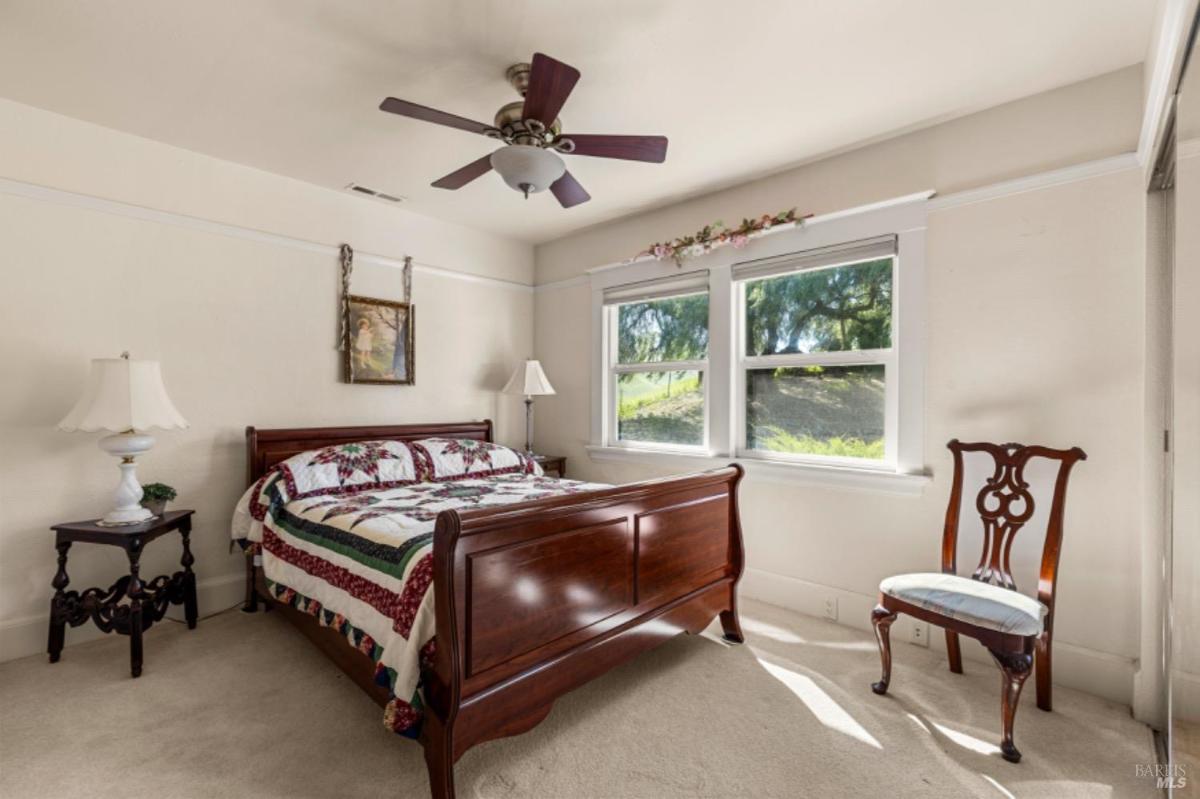 Bedroom with a wooden bed frame and two windows.