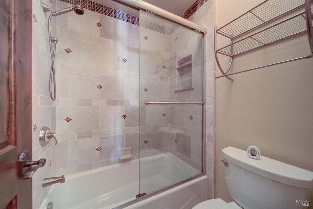 A bathroom featuring a glass shower enclosure, bathtub, and tiled walls.