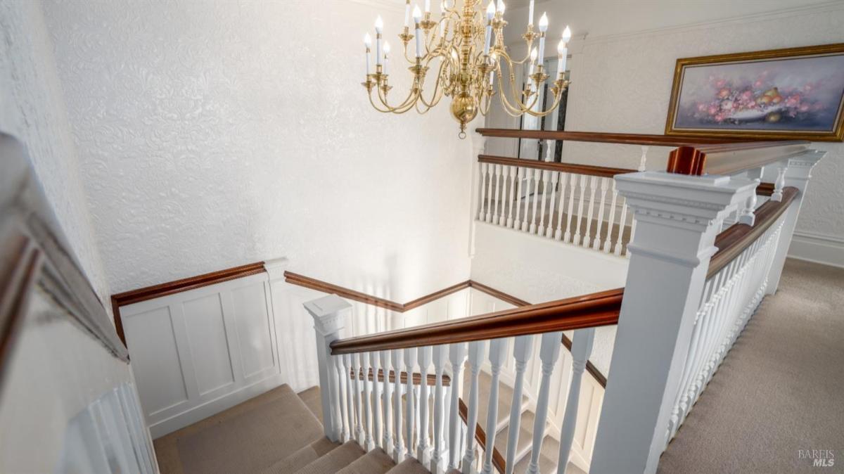 Staircase with white railing and chandelier.