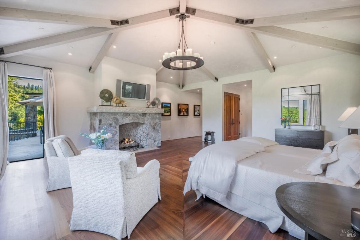 Bedroom with a beautiful stone fireplace, a large bed, and comfortable seating. 