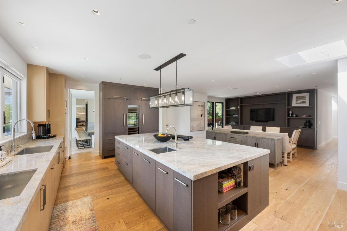 A kitchen with a marble island, built-in cabinetry, and open space leading to a living room.