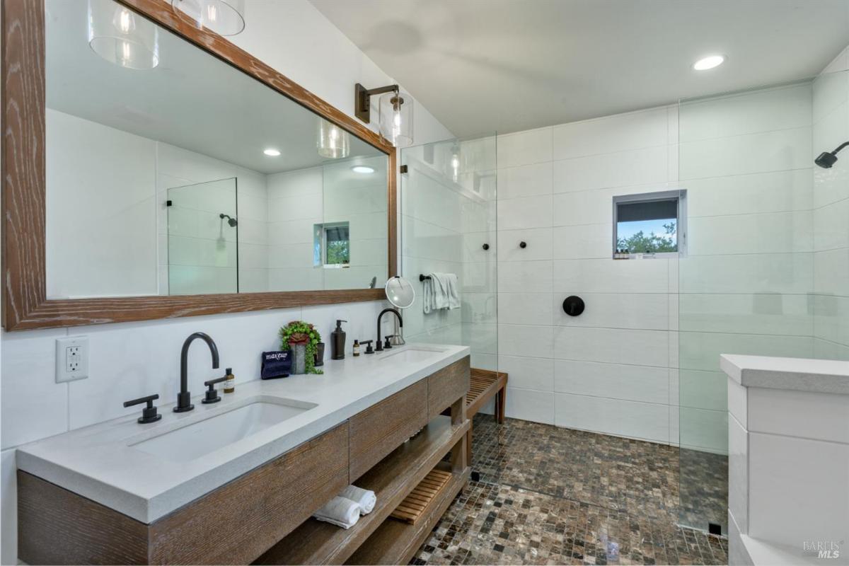 Bathroom with a walk-in shower, double vanity, and wood accents.