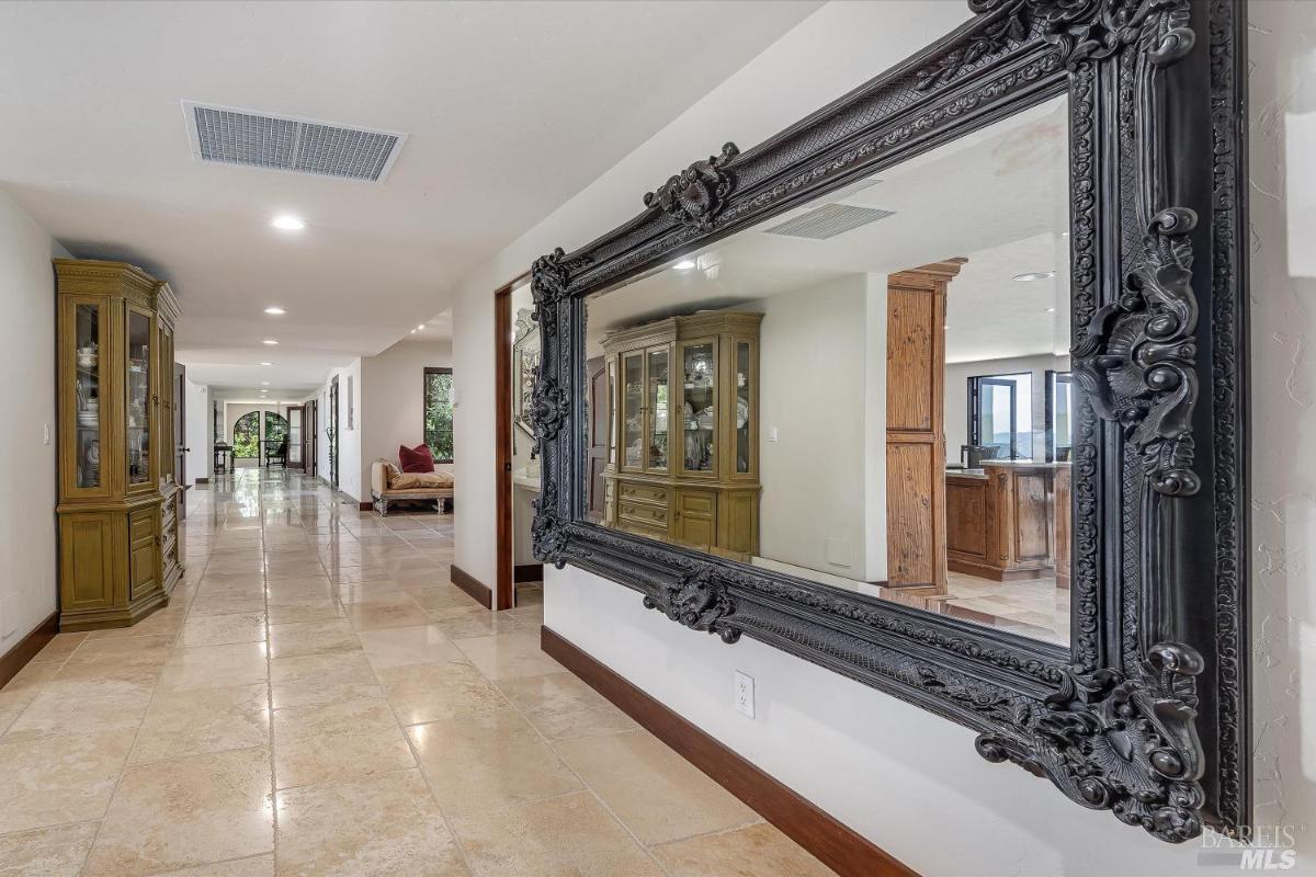 A hallway with a large decorative mirror and tiled flooring.