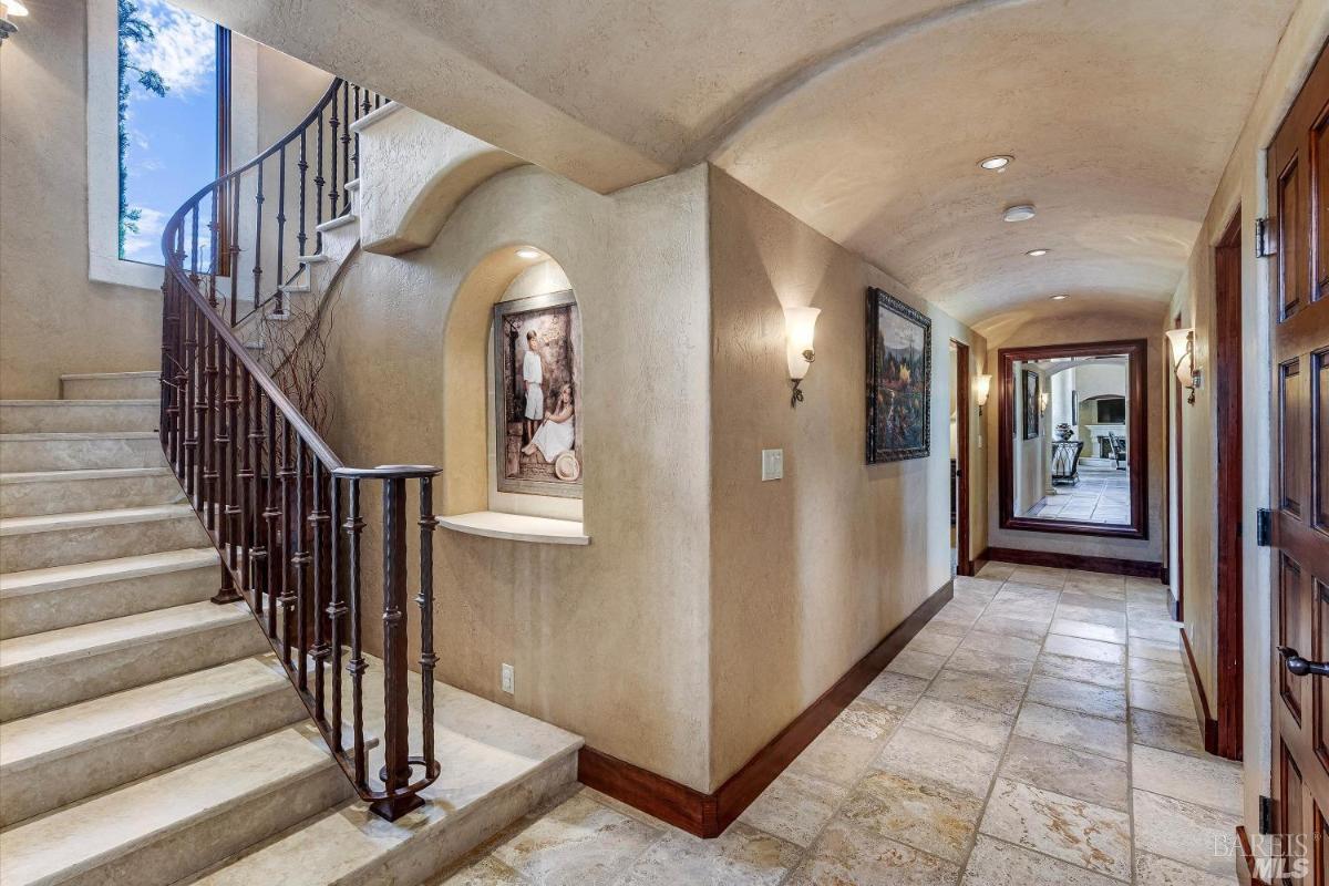 A hallway with a curved staircase and decorative wall niches.