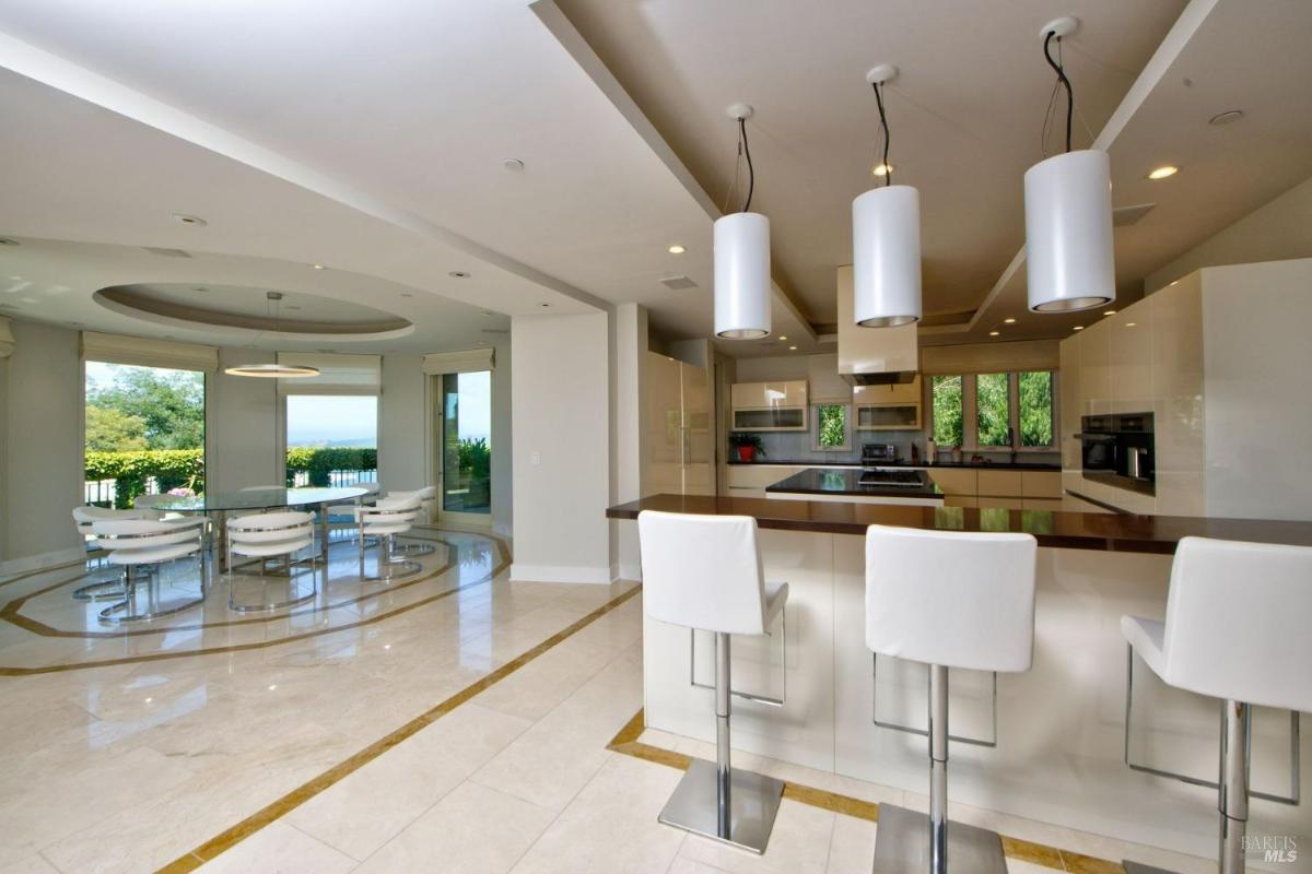 Kitchen with an island, bar seating, and pendant lighting, connected to a dining area with scenic views