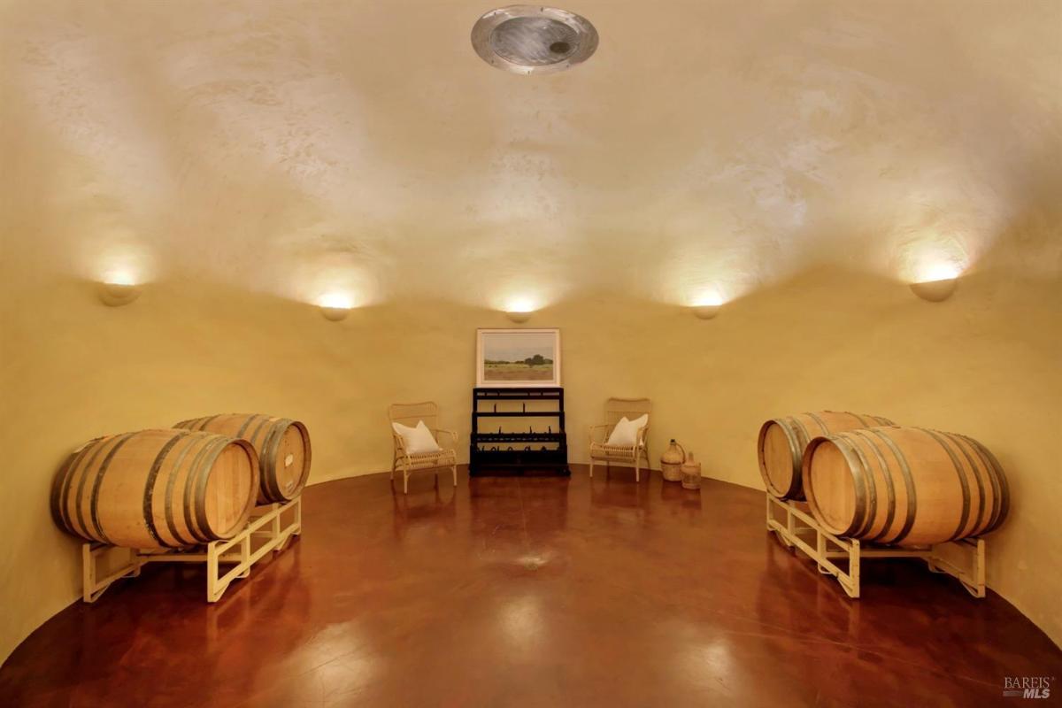 A wine storage room with barrels and a rack on a polished floor.