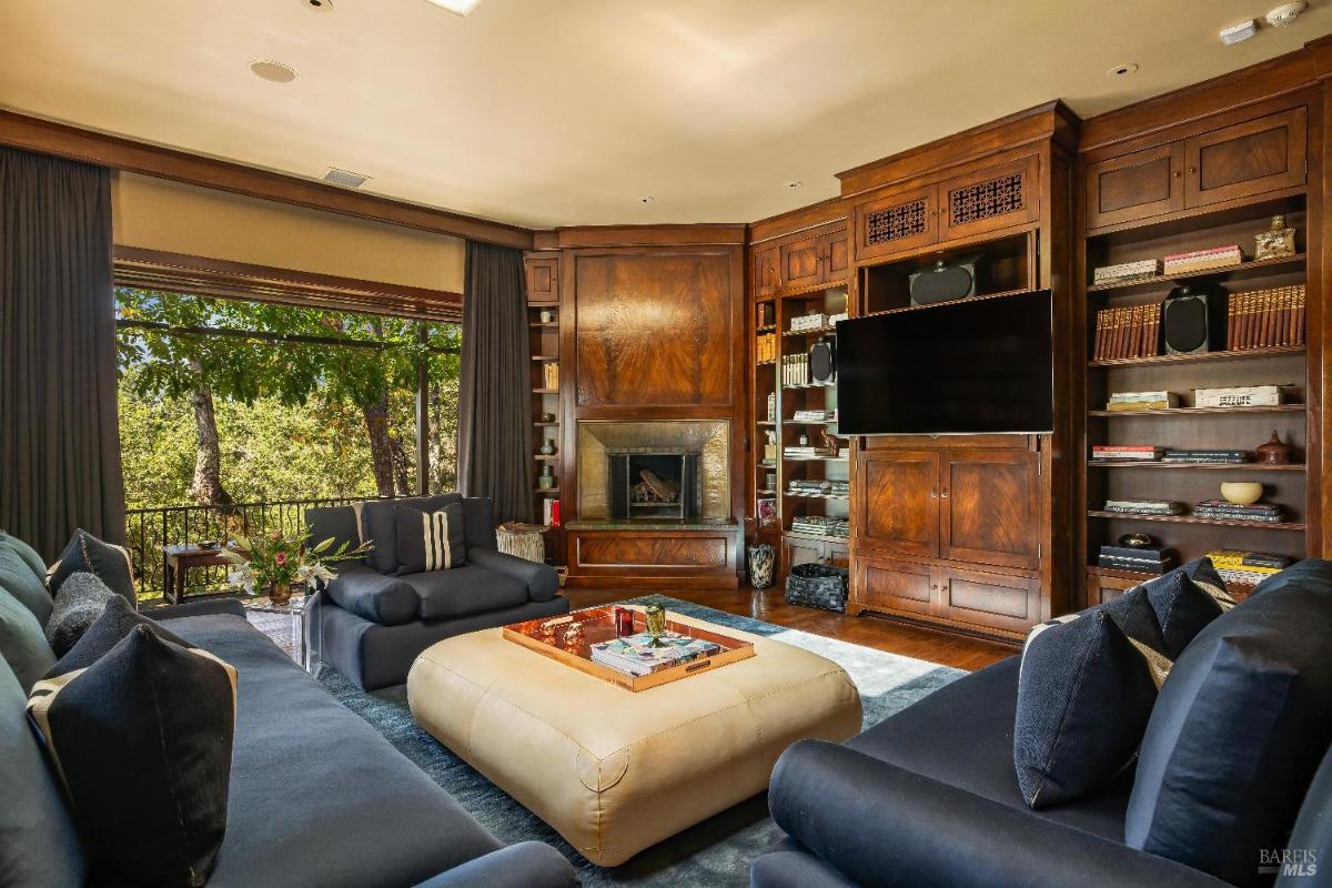 Family room with built-in wooden shelves, a fireplace, and a large ottoman.