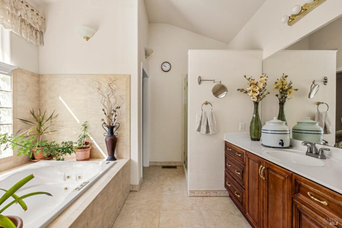 Bathroom with a soaking tub, double vanity, and tiled walls.