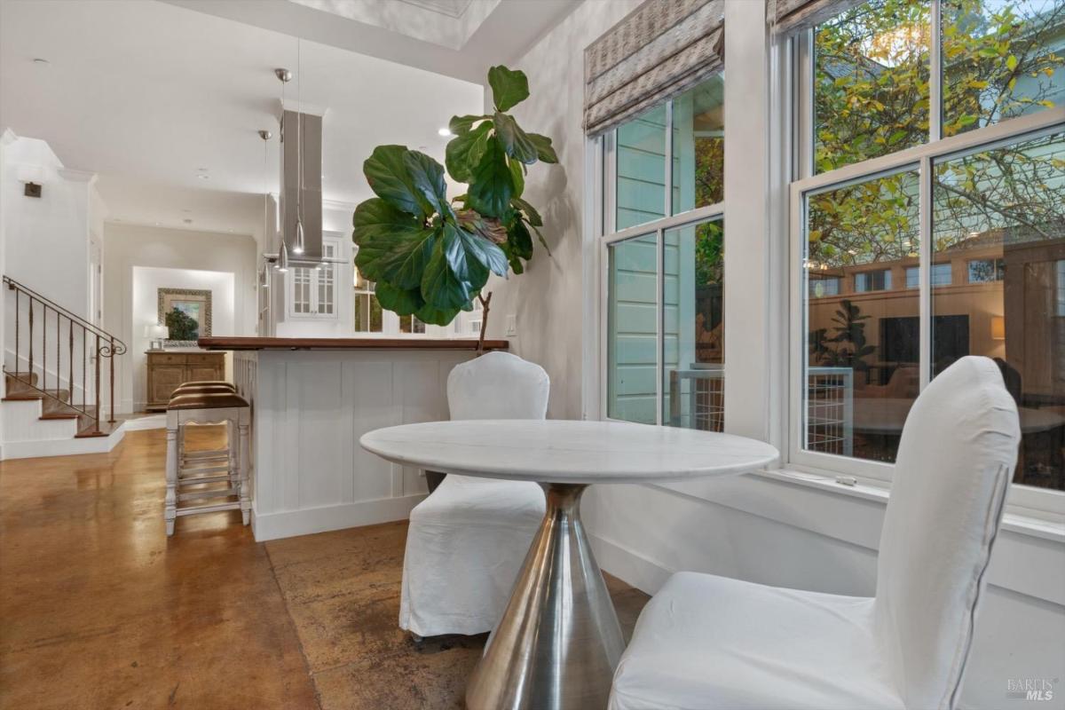 A small table and two chairs near windows overlooking greenery.