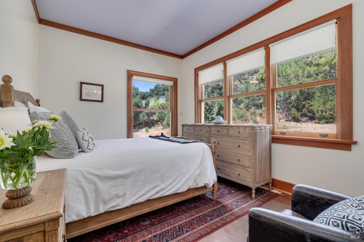 Bedroom with a bed, dresser, and windows with outdoor views.