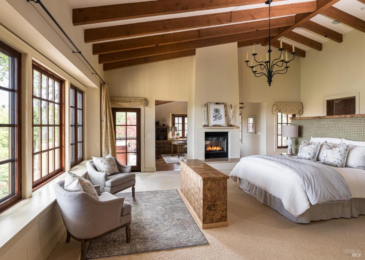 Bedroom with a fireplace and seating area by windows.