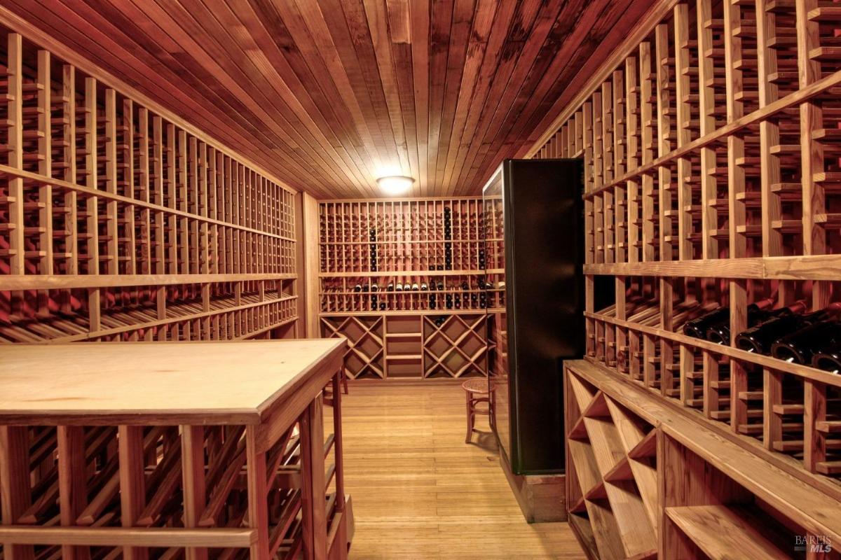 Wine cellar with floor-to-ceiling wooden racks and ample storage space for bottles.