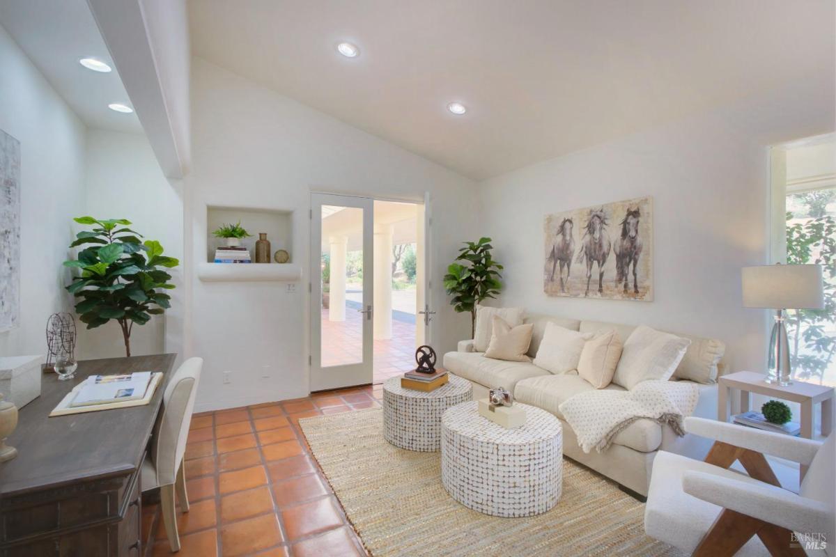 A sitting room with a desk, sofa, and double doors leading to an outdoor patio.