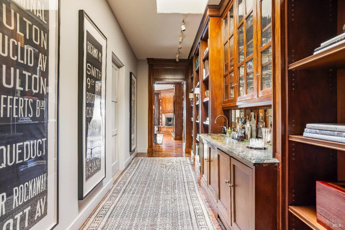 Hallway with a wet bar, wooden cabinets, and framed posters on the wall.