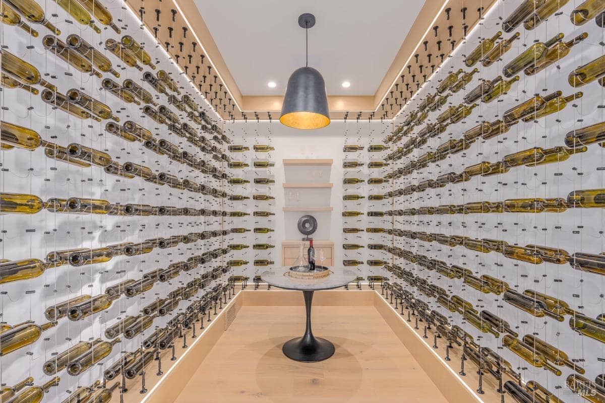 A wine cellar with wall-mounted bottle racks, a round tasting table, and modern lighting.