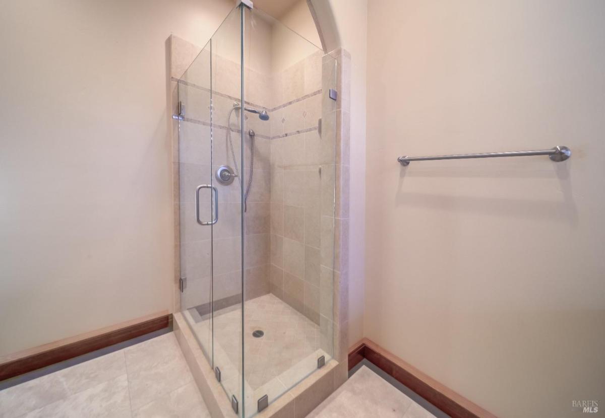 A glass-enclosed shower with a tiled floor and wall-mounted fixtures.