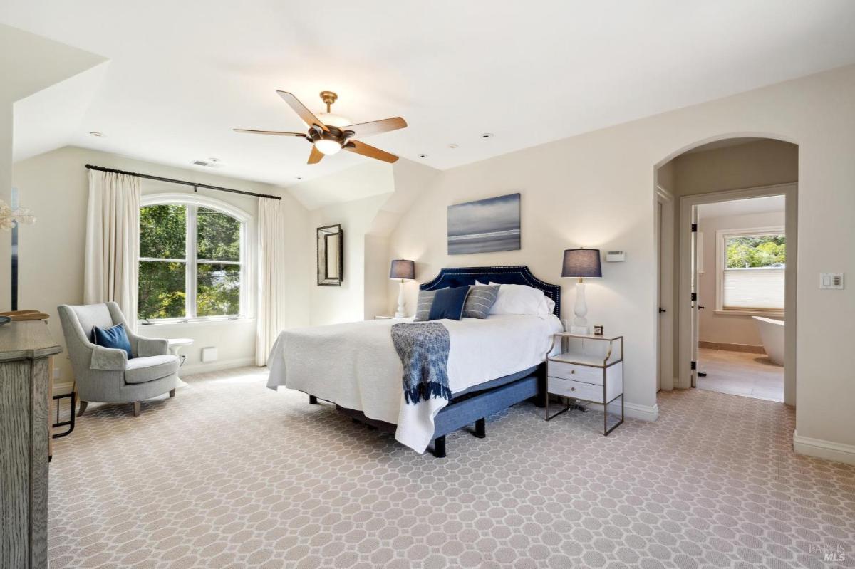 A primary bedroom with large windows, a ceiling fan, and an en suite bathroom.