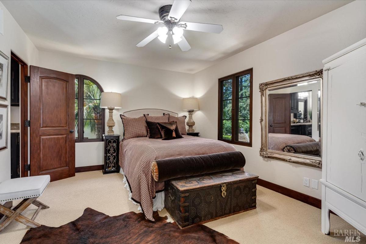 A bedroom with a bed, arched window, and a trunk at the foot of the bed.