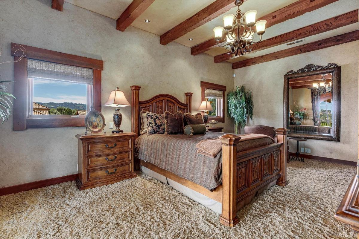 A bedroom with exposed wood beams and a large mirror.