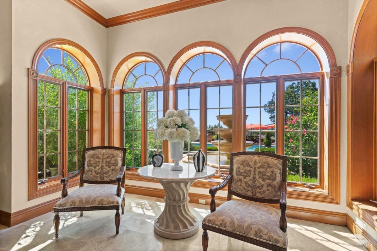 Sitting area framed by arched windows overlooking the garden fountain.