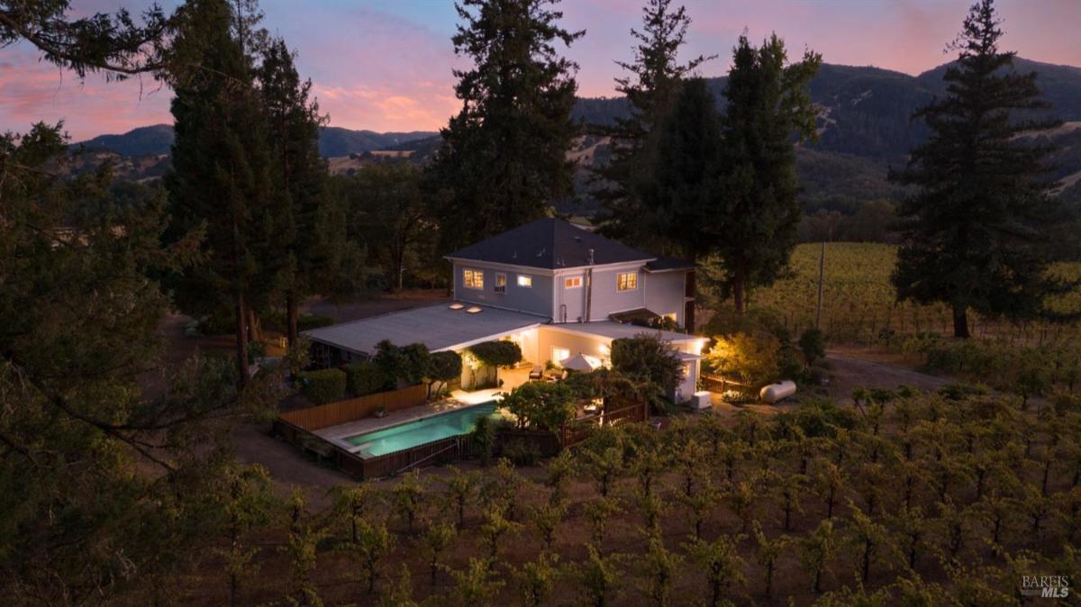 Aerial view of a house surrounded by vineyards at dusk.