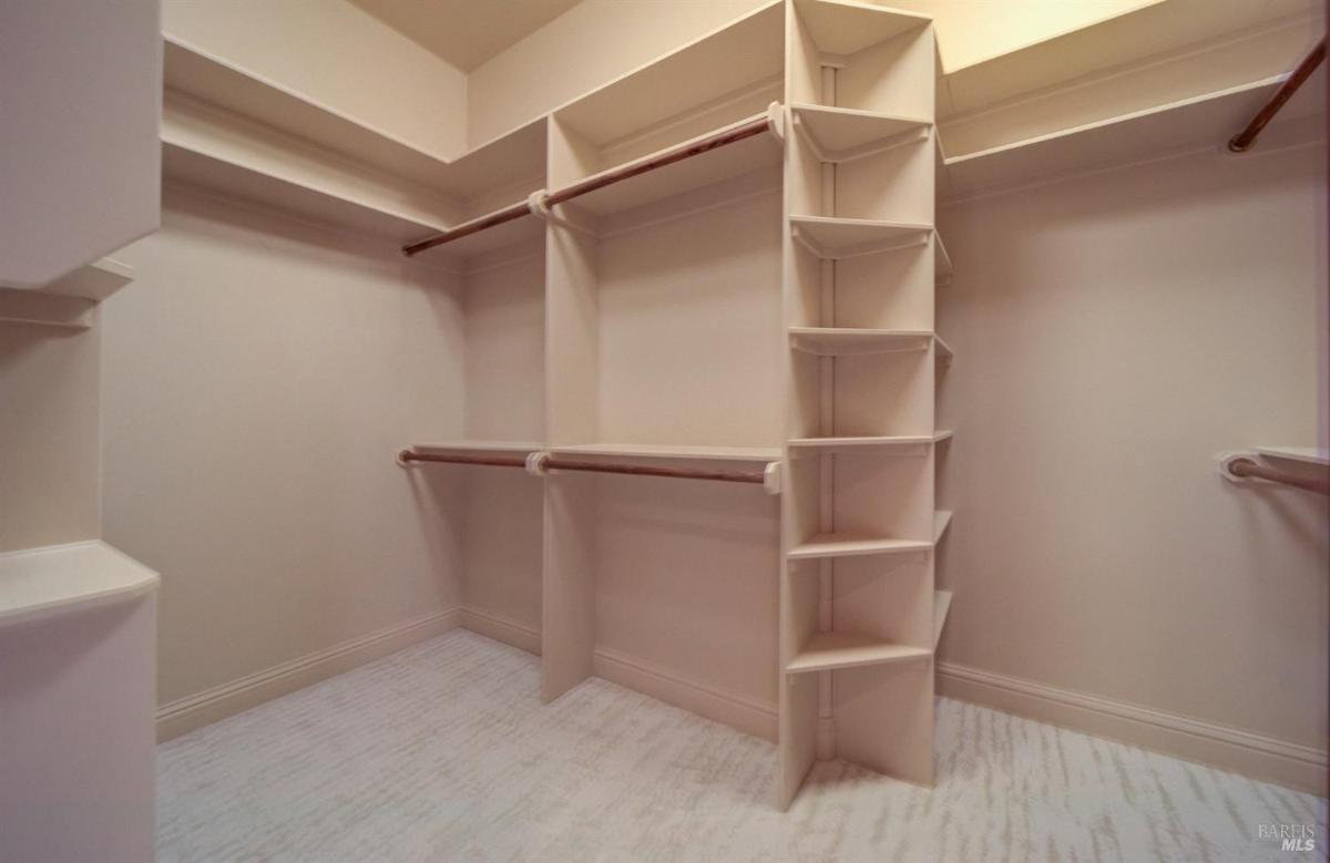 A walk-in closet with built-in shelving and multiple hanging rods.