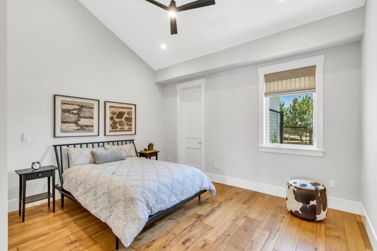 A bedroom features a bed, a nightstand, and a window with a view.