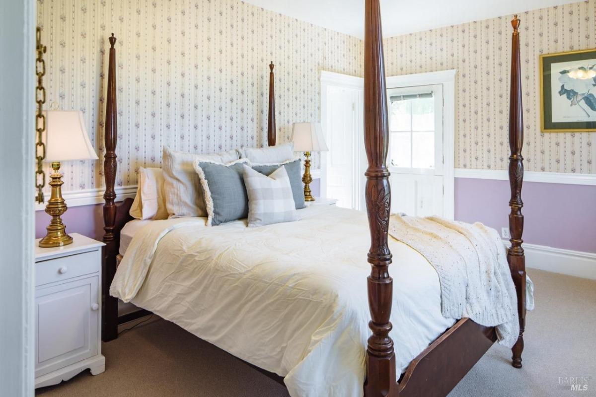 A bedroom featuring a four-poster bed with white bedding and a side table.