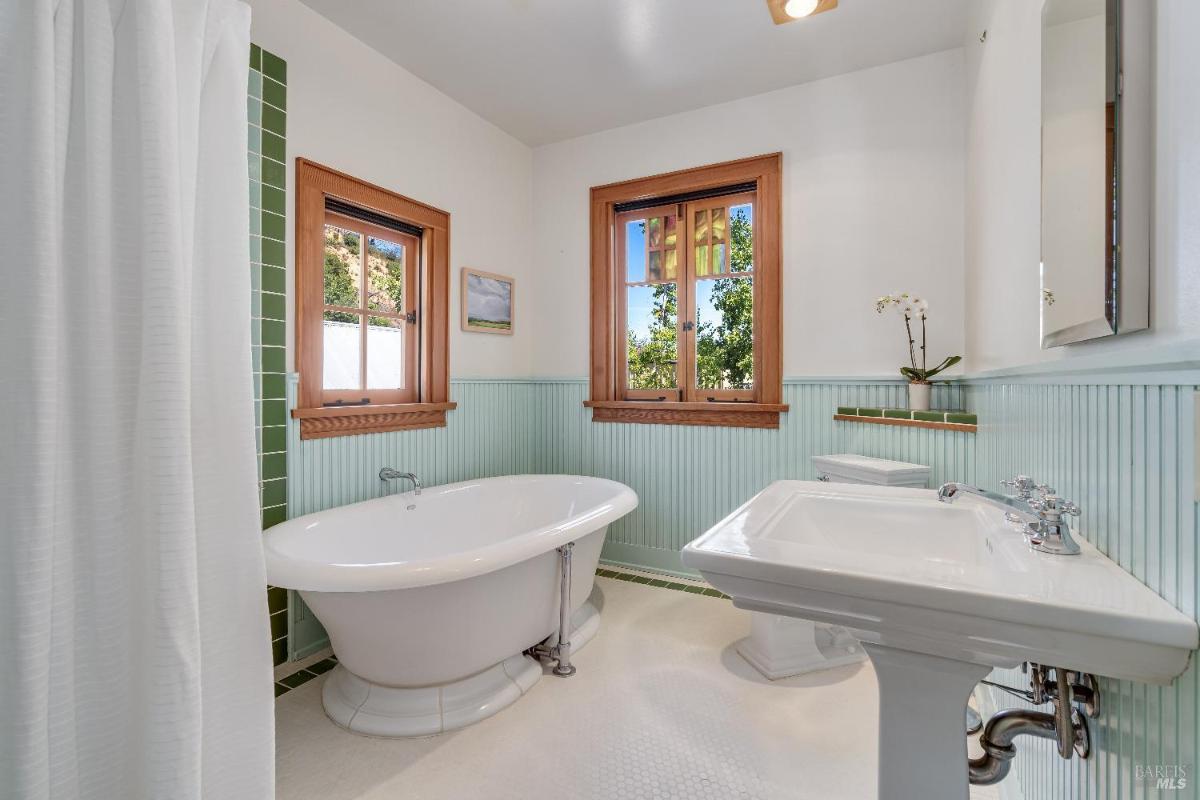 Bathroom with a freestanding tub, sink, and windows.