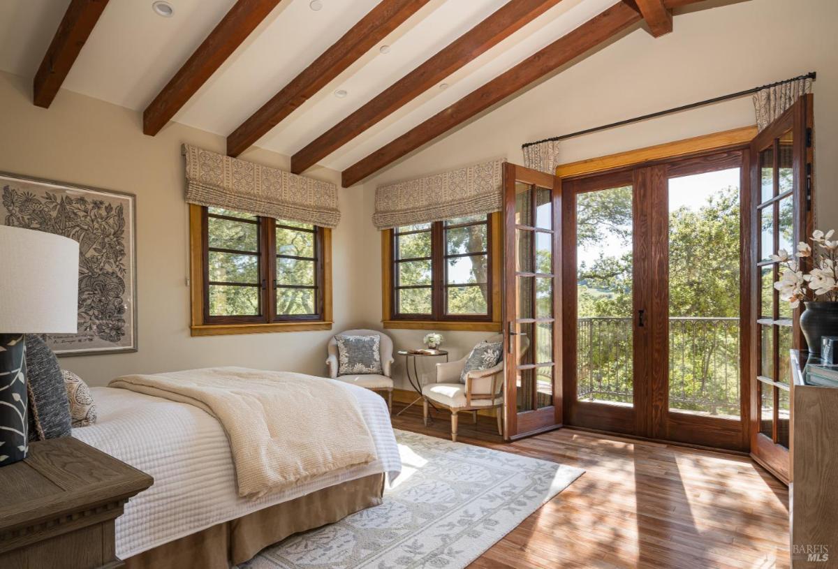 Bedroom with wooden beams and balcony access.