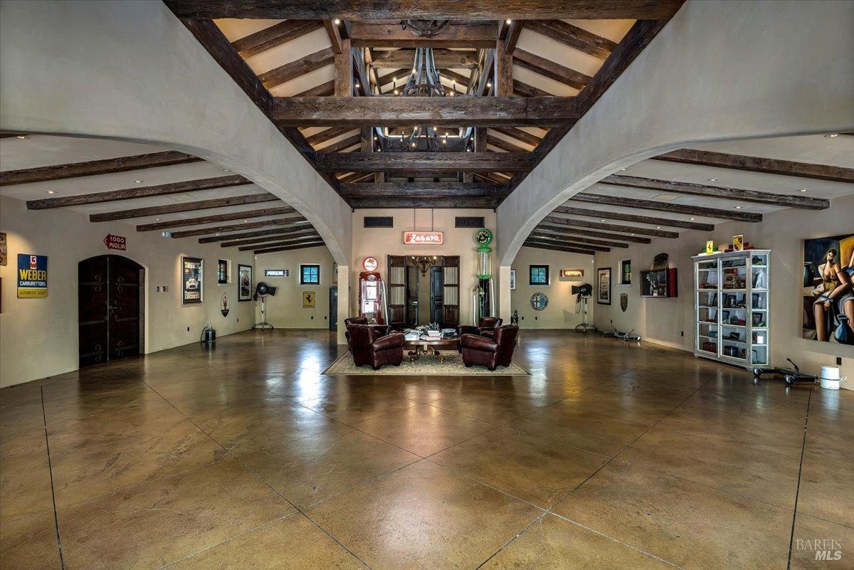 A spacious room with exposed wood beams, polished floors, and vintage decor.